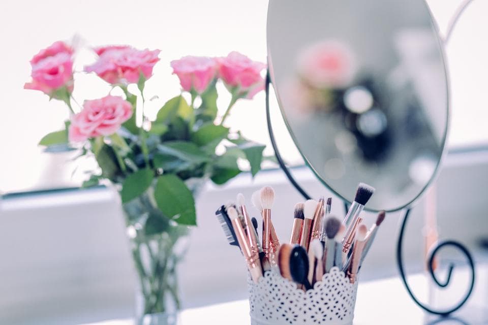 Roses and makeup brushes on a bright vanity windowsill